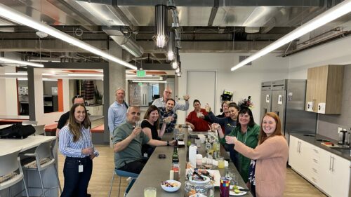 A group of coworkers celebrating in an office kitchen.