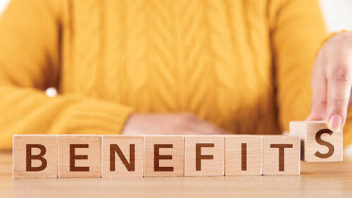 A woman with 'Benefits' spelled out on wooden blocks in front of her.