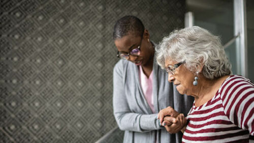 A caregiver helping an older woman down the stairs