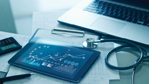 A tablet on a desk with graphs on it next to a stethoscope