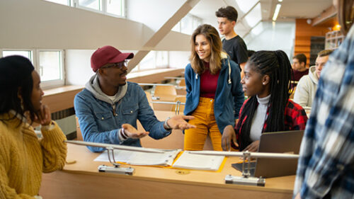 A group of diverse college students working on a project together in a lecture hall.