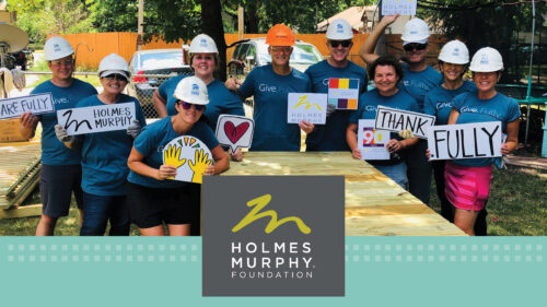 A smiling group of Holmes Murphy employees with hard hats on with the text: Give.Fully. Community Impact Report 2022-2023