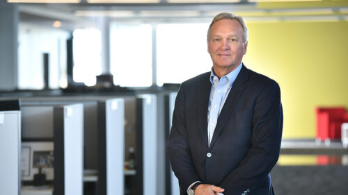 Craig Hanson, a white man in a black suit with a blue button up.