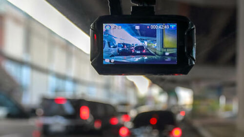 A small camera connected to a windshield recording the traffic.