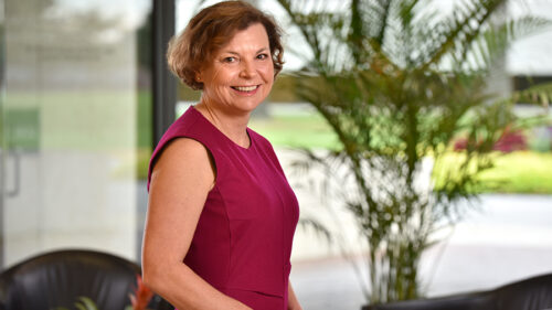 Ellen Willadsen in a professional red dress with a greenery background