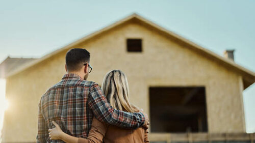 A couple looking at the outside of the home they are building