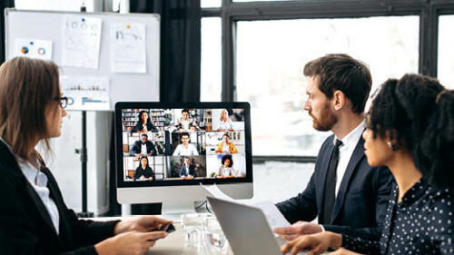 Office workers in a conference room talking to people on a zoom call.