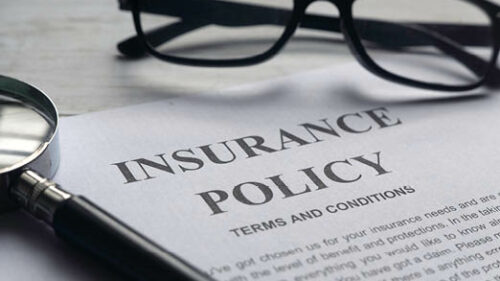 Insurance paperwork on a desk with glasses.