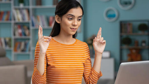 A woman crossing her fingers at a desk working