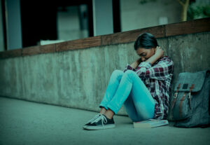 A girl sitting on the floor struggling with her mental health.