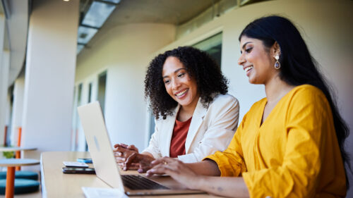 Two women talking over a computer