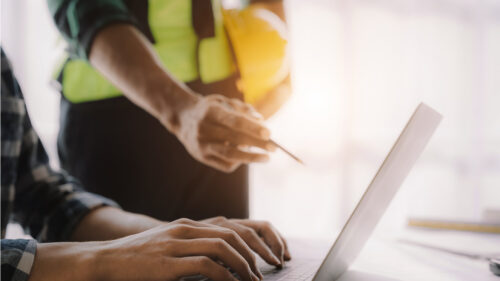 Two construction professionals discussing over a computer