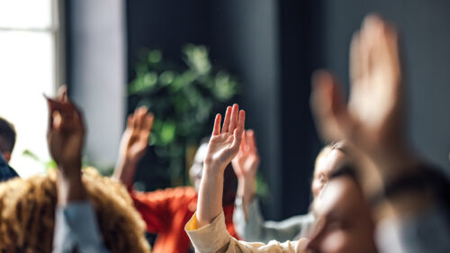 A group of professionals raising their hand.