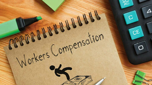 A notebook with workers compensation written on it with a cartoon of a person and money