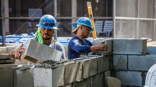 two brick layers working outside on a construction site